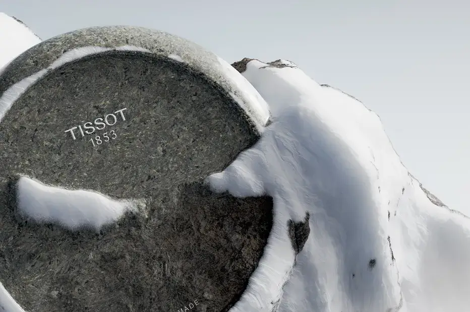 Logo Tissot 1853 wygrawerowane w granicie, symbolicznie zatopione w alpejskim śniegu